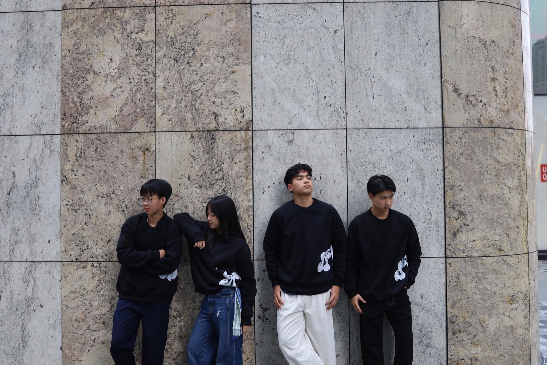 The NEVERTELL team standing against a stone wall in the brand’s black pieces